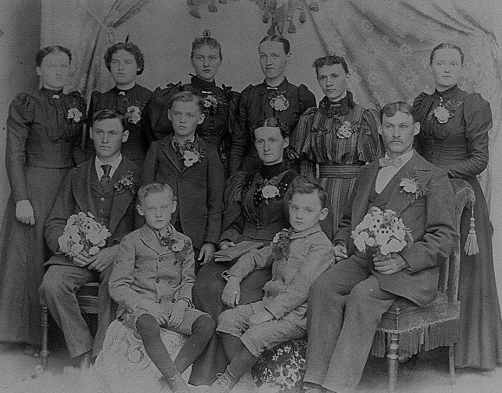 black and white historical photo of family with man, woman, six daughters and four sons wearing mid-1890s clothing